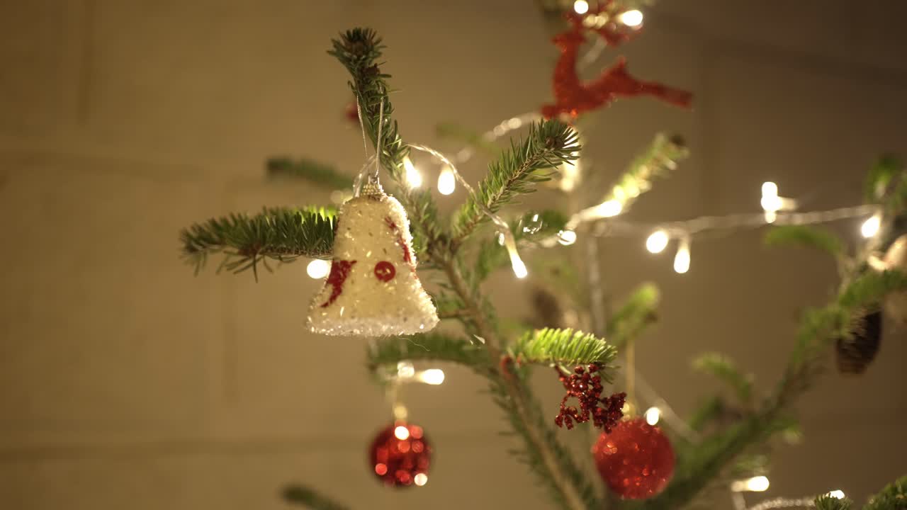 Decorated Christmas tree with glowing fairy lights, red baubles, and a festive bell