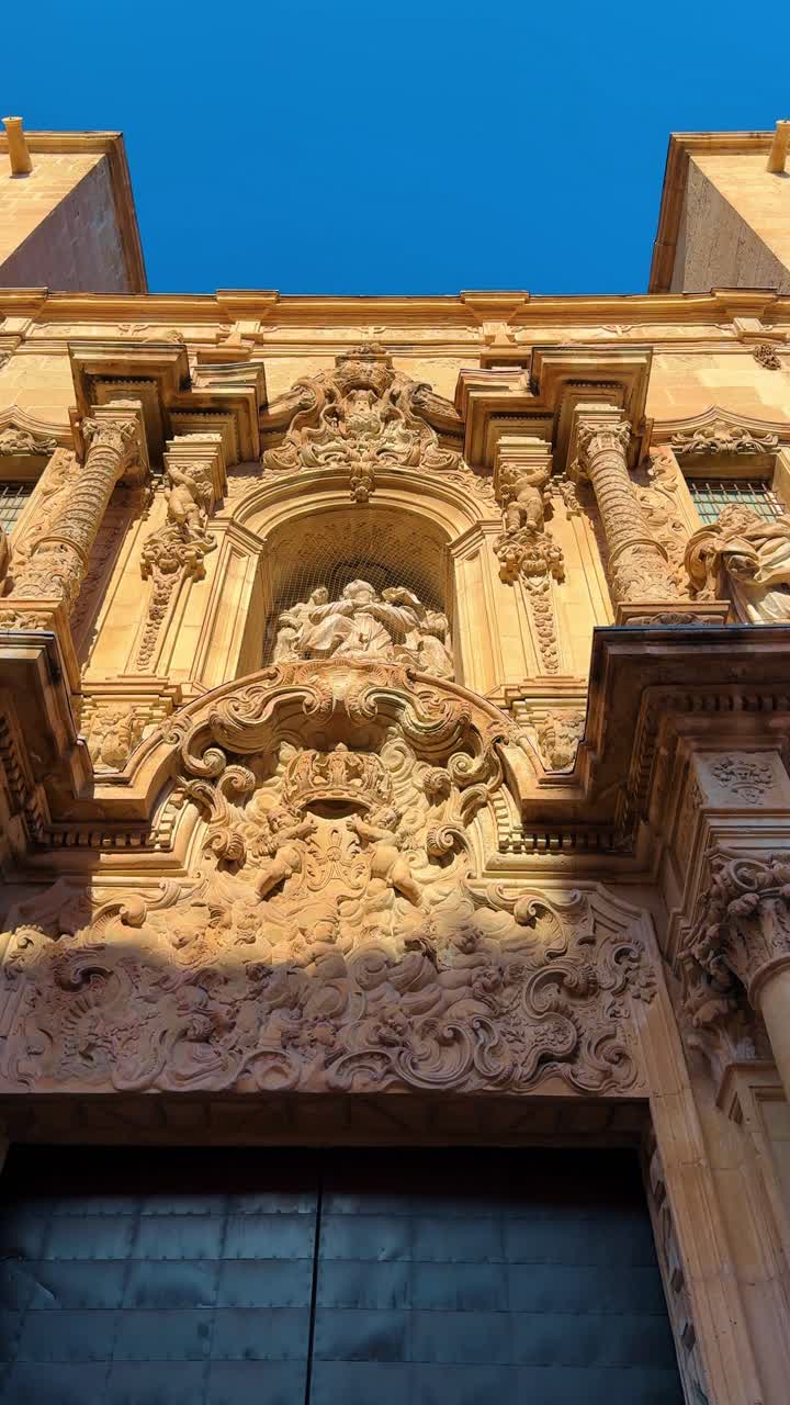 Dettaglio architettonico dell'ingresso di una chiesa barocca in Spagna. Vista dettagliata del portale centrale e delle sculture religiose su una storica facciata di chiesa in pietra calcarea.