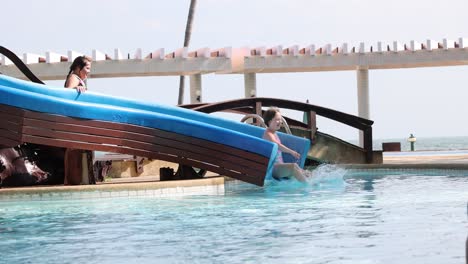 people sliding into water from a blue slide