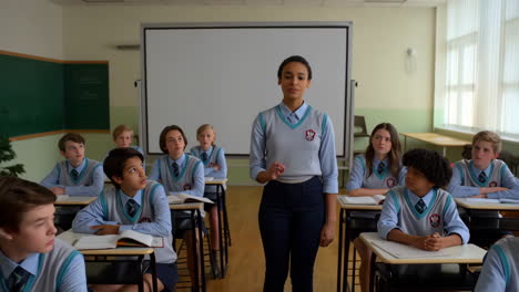 students in uniform in a classroom setting, with one student presenting