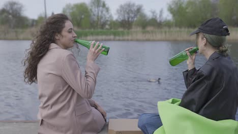 川辺で話したりビールを飲んだりする友達のペア