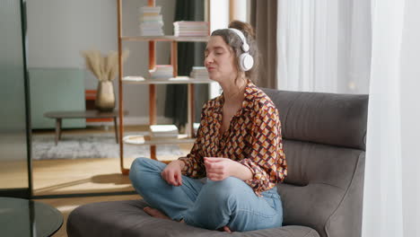 young relaxed happy woman listens to music in headphones at home, pan