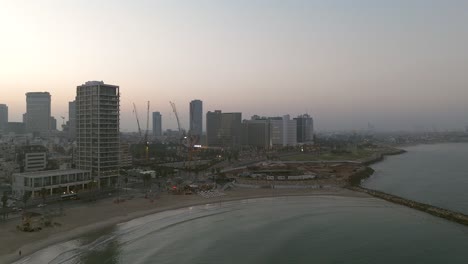 Tel-Aviv-coastline-at-sunrise-with-beautiful-calm-waters-of-The-Mediterranean-Sea,-Waterfront-hotels-and-light-sun-flare