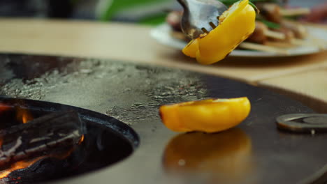 Man-chef-putting-vegetables-in-plate-outside.-Guy-taking-bell-pepper-from-grill