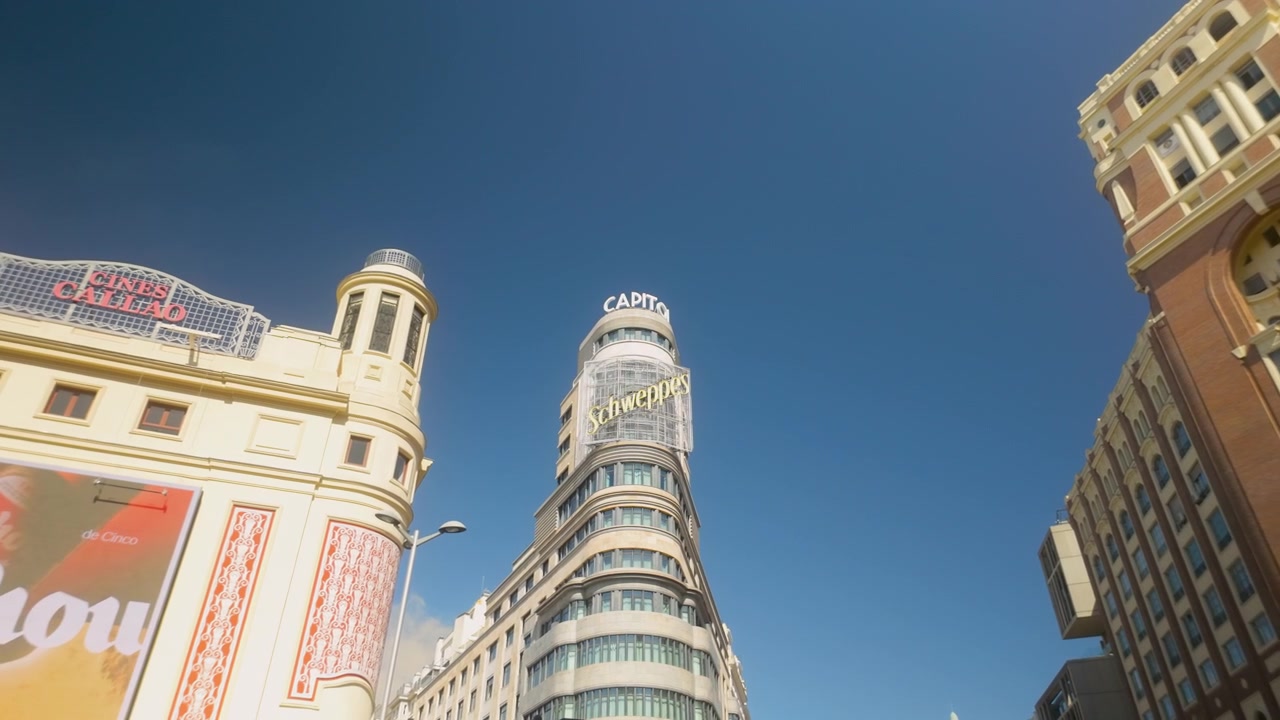 Vista dal basso della famosa insegna Schweppes e dell'edificio Capitol sulla Gran Via. Ideale per documentari di viaggio, lifestyle urbano e contenuti sul turismo spagnolo