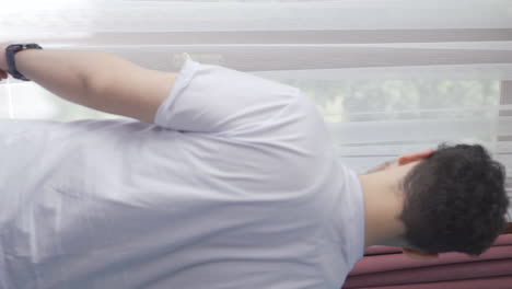 Vertical-video-of-The-man-who-opens-the-curtains-yawns-and-relaxes.