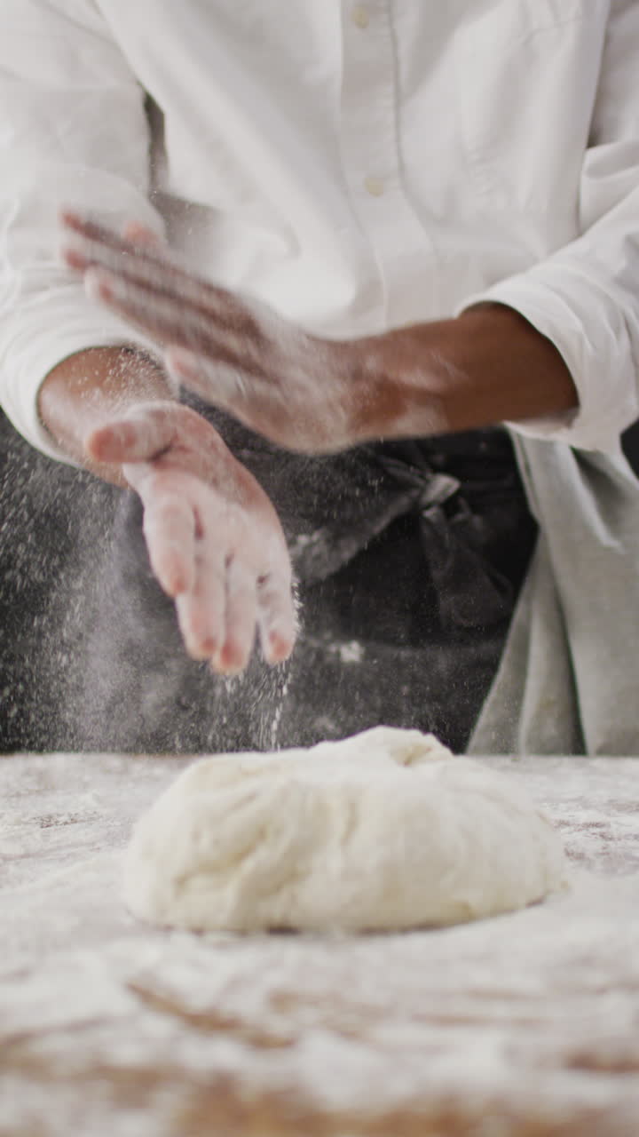 베이커가 반죽을 기 전에 손에 밀가루를 는 중간 부분의 수직 비디오