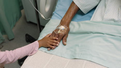 niña tocando la mano del abuelo acostado en la cama del hospital niño mostrando afecto al lado de la cama para el abuelo recuperándose de la enfermedad atención médica apoyo familiar