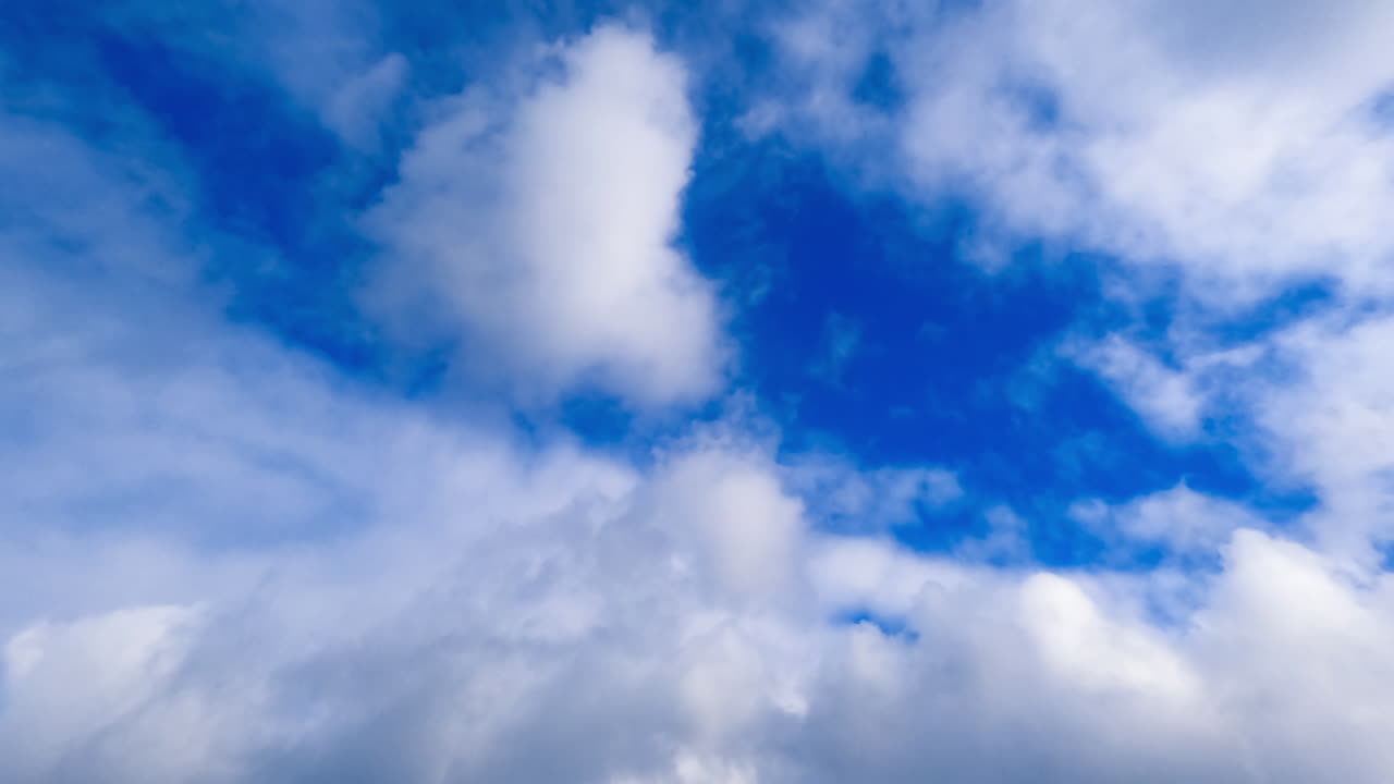 Blue sky with clouds flowing over. Timelapse of fluffy clouds motion.