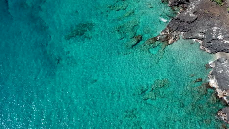 Kristallblaues-Wasser-Am-Schwarzen-Sandstrand-Auf-Big-Island-Hawaii-Mit-Brandung-Auf-Felsen