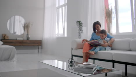 Portrait-of-little-cute-boy-reading-book-with-mother-while-sitting-on-safe