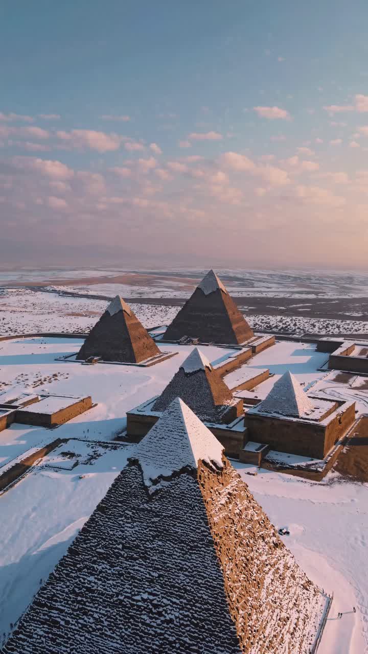 Aerial video shot of snow-covered pyramids at sunset, showcasing an expansive landscape