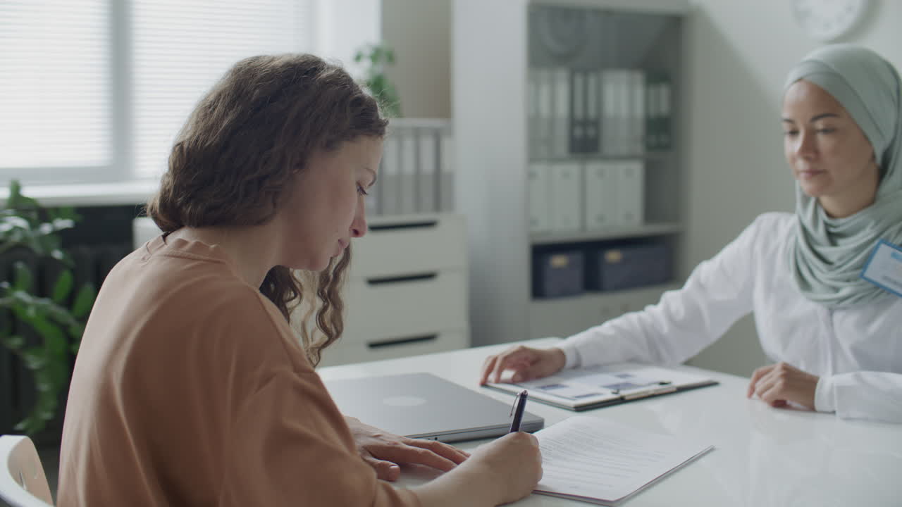 Muslim Female Doctor Giving Handshake to Patient after Signing Medical Agreement