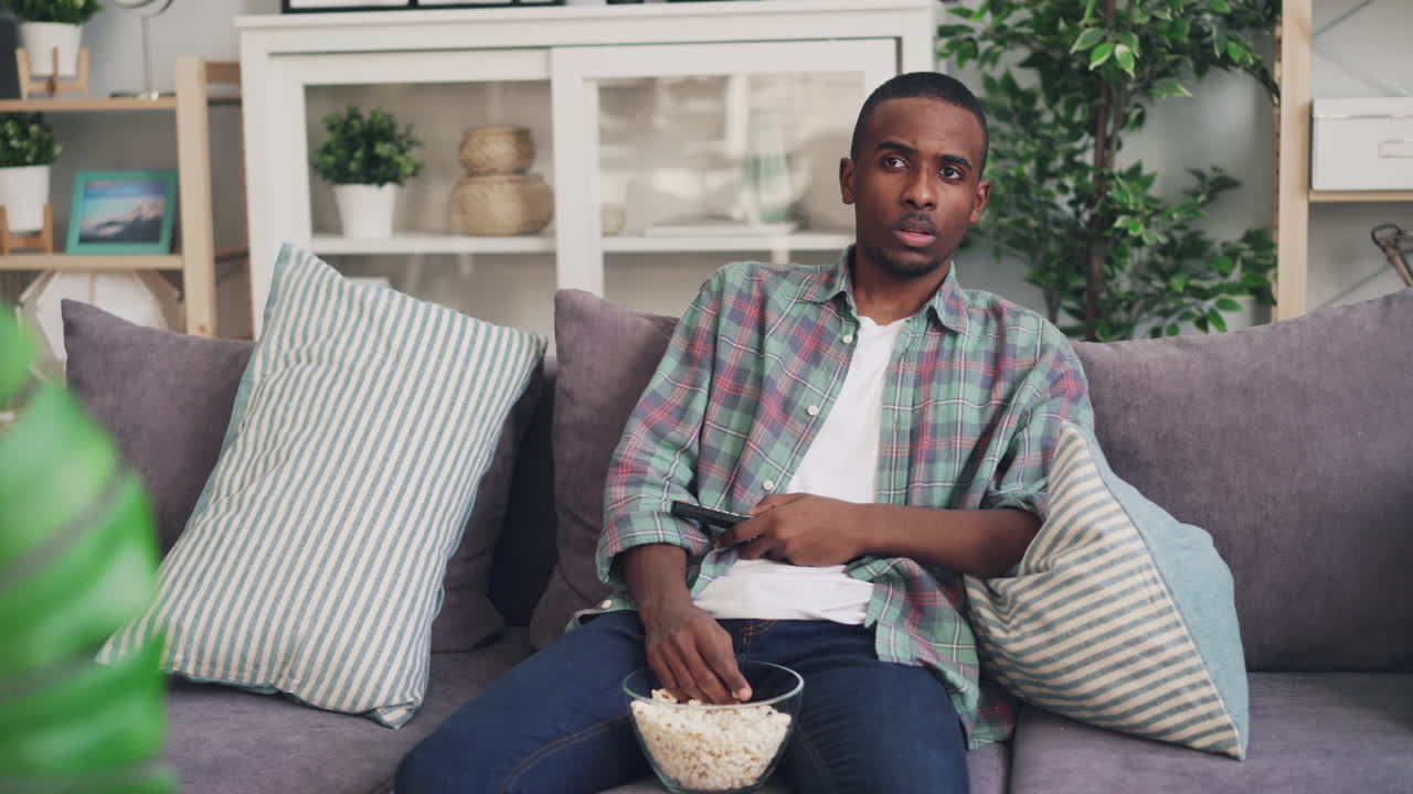 Man Watching TV on Couch with Popcorn