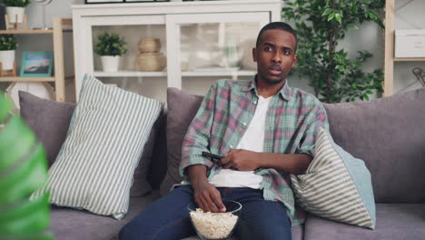 man watching tv on couch with popcorn