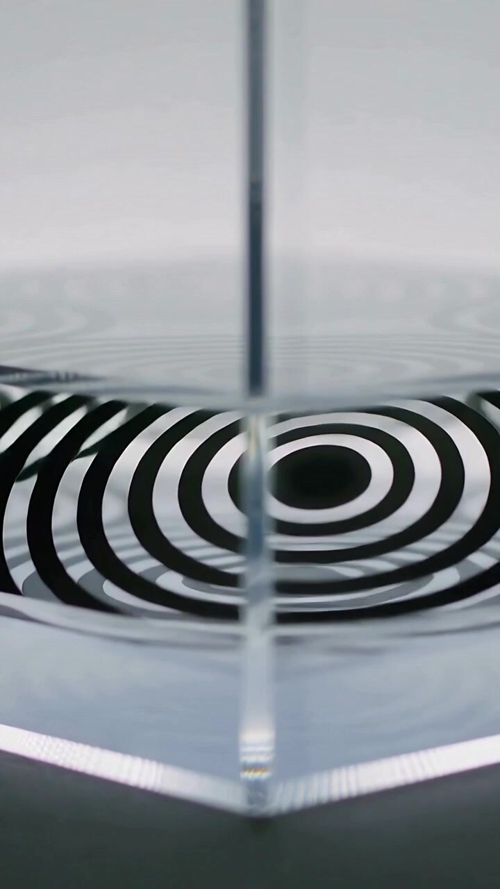Vertical video: Droplet hitting rim, water forming waves under glass panel in studio warping rings