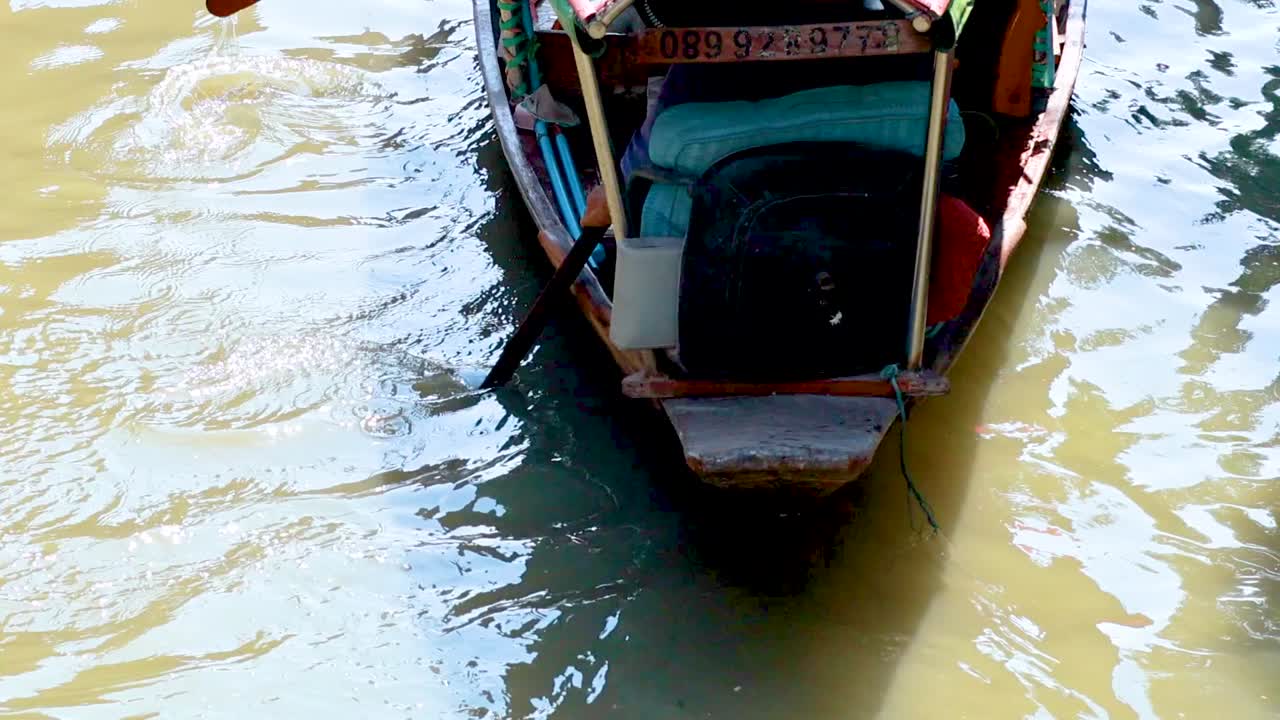 un barco se mueve a través de un canal en bangkok, tailandia, mostrando técnicas tradicionales de remo bajo luz natural