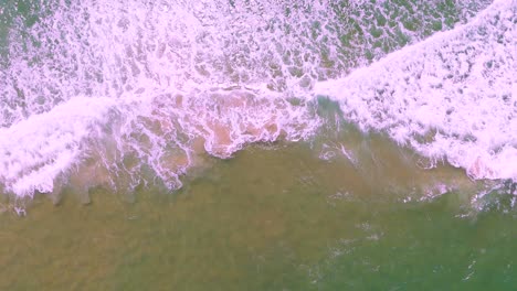 waves crashing on sandy beach from above