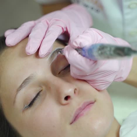 cosmetologist is performing a permanent eyebrow makeup procedure for the client. modern cosmetology