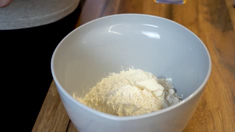 woman adding a spoon of flour to a bowl