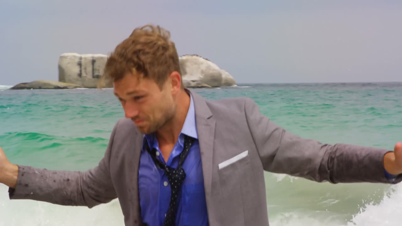 4k 해변에서 브리프케이스를 들고 바다에서 달리는 백인 사업가의 앞면