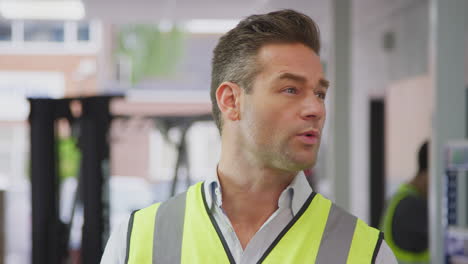 portrait of male worker in logistics distribution warehouse wearing high-vis safety vest