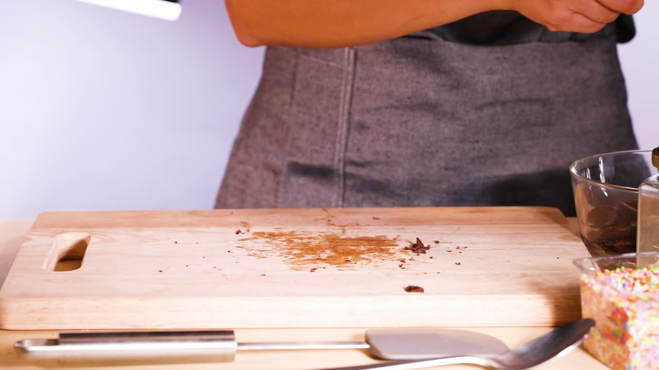 Persona che trita cioccolato su un tagliere di legno