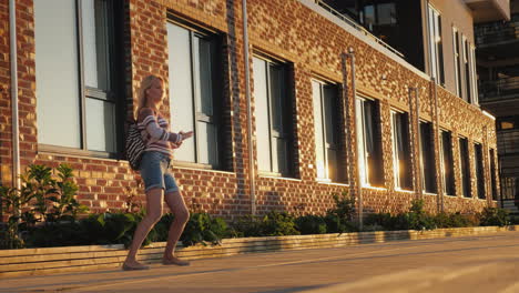 a carefree middle-aged woman listens to music and dances on the street near a beautiful brick buildi