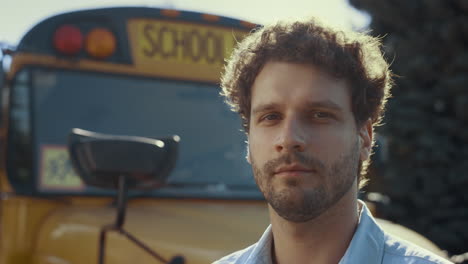 closeup schoolbus chauffer face at vehicle. handsome man driver looking camera.