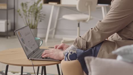 man with prosthetic leg looking at business diagrams on laptop