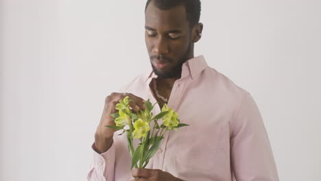 chico guapo oliendo y tocando las flores en su mano