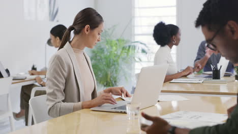 Businesswoman-working-on-a-laptop-in-a-busy-office