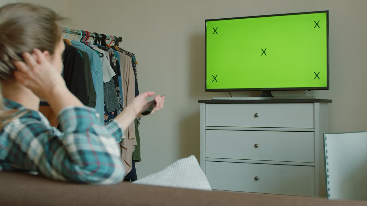 lviv, 우크라이나 - 2020 년 5 월 18 일: 젊은 여성이 소파에 앉아 수평 녹색 화면 모을 가진 tv를보고 있습니다.