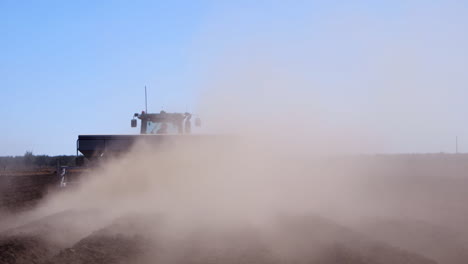 plow tilling the field while its dry and kicking up a cloud of dust