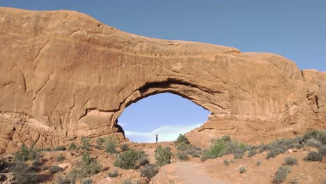 Pequeña-Persona-De-Pie-Dentro-De-La-Ventana-Norte-En-El-Parque-Nacional-Arches,-Utah---Cámara-Lenta