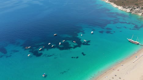 boats anchored in crystal clear turquoise waters along a beautiful sandy beach in albania