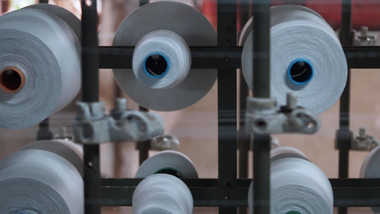 Close-up of numerous white yarn spools in a textile factory