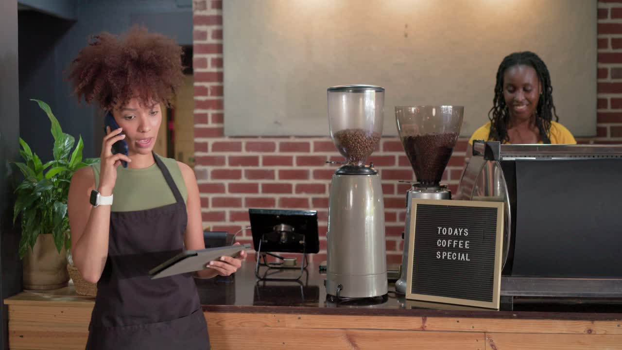 Bariste afroamericane rispondono a una chiamata, controllano il tablet al bancone del bar e preparano il caffè