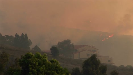 Long-Shot-Of-A-Helicopter-Dropping-Chemicals-Over-Fires-Raging-Around-A-Southern-California-Community