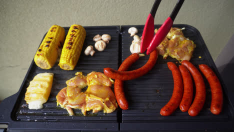 Person-Turning-Hot-Dog-Sausages-On-Griller-Using-Silicone-Tongs