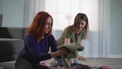 best girl friends pack things to go on trip sitting on floor