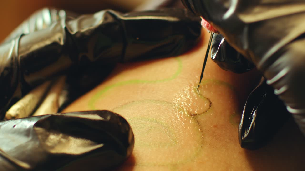 Hands of Tattoo Artist Putting Black Ink into Skin with Needle