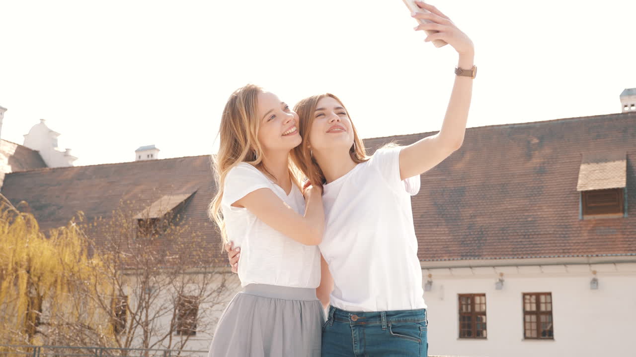 두 명의 젊은 여성이 야외에서 셀피를 찍고 있습니다.