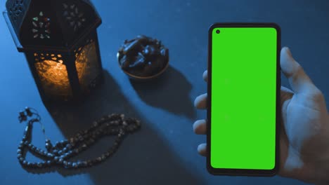 Wide-Shot-of-Lantern-Water-and-Dates-with-a-Green-Screen-Phone-at-Dusk