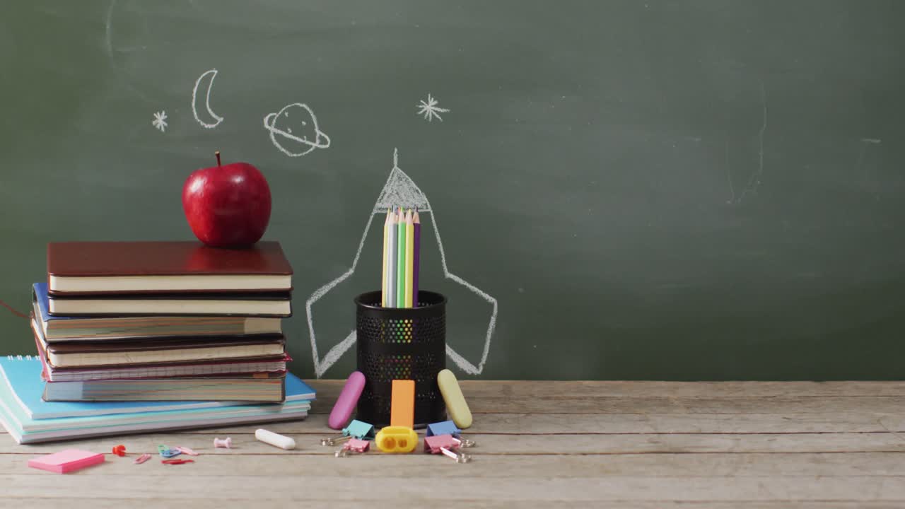 video de suministros escolares y libros en una mesa de madera sobre una pizarra