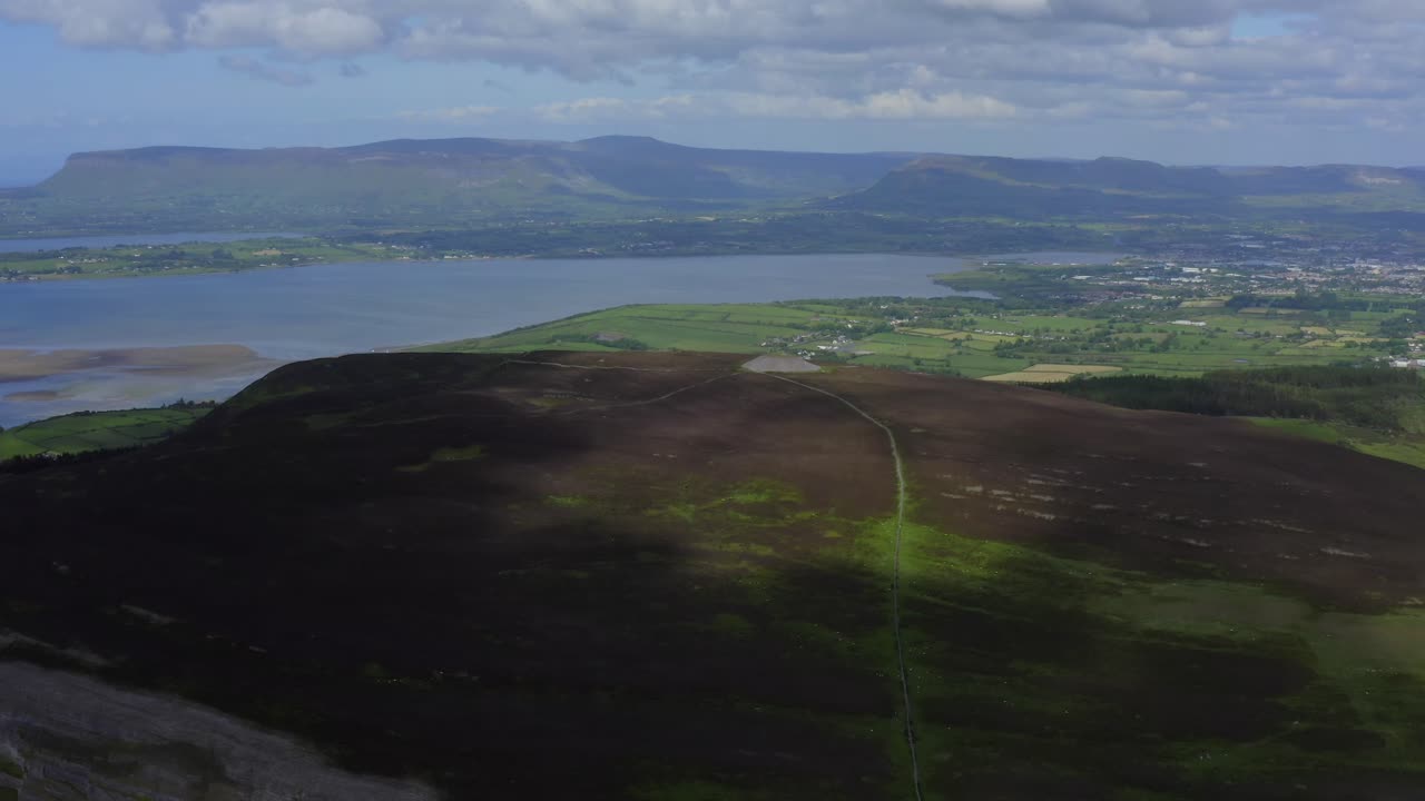 Knocknarea, Coolera peninsula, Sligo, Ireland, June 2021. Drone slowly orbits the southern face with Queen Meave's Grave at the summit and views of Sligo Bay and Benbulbin moutain in the distance