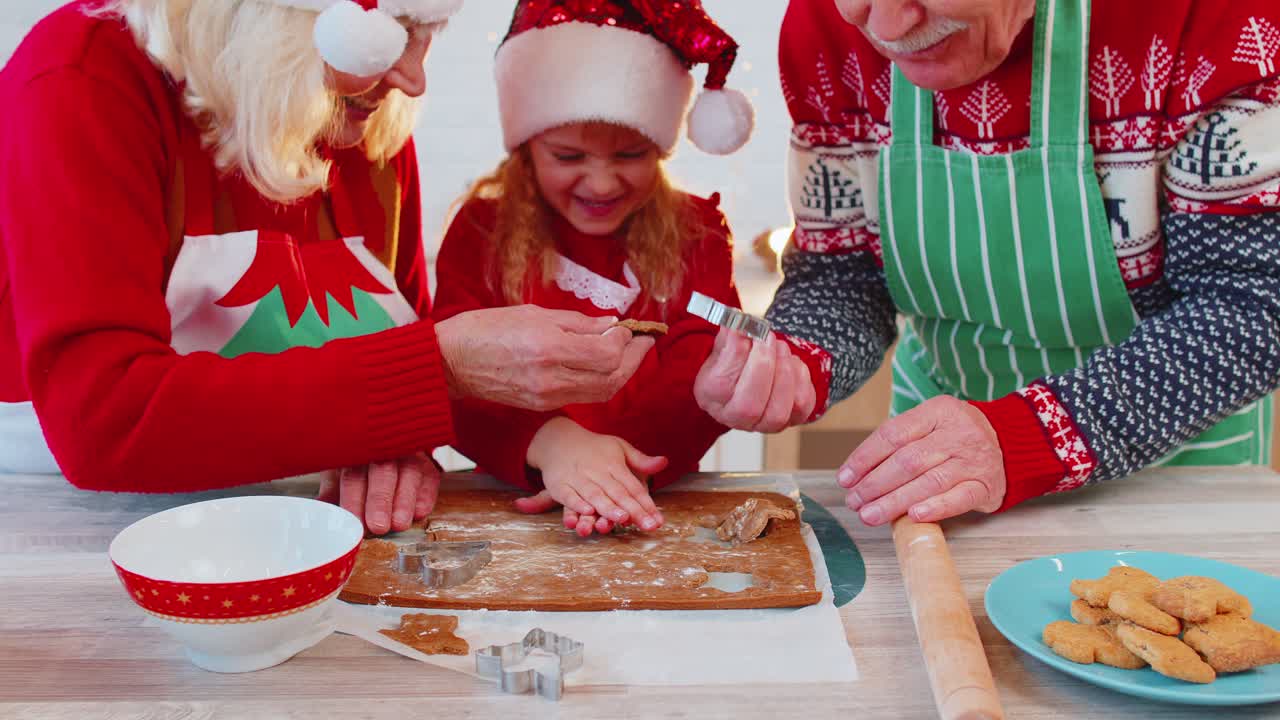 abuelos de familia mayores con nieta con sombreros de santa claus preparando, cocinando galletas caseras