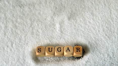 dice spelling sugar falling into pile of sugar