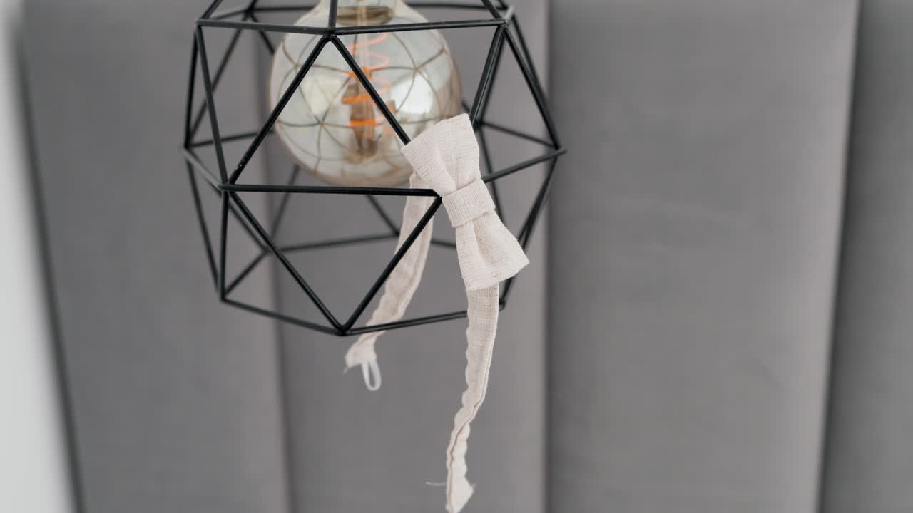 Stylish wire frame light bulb adorned with a delicate white ribbon bow in a modern space