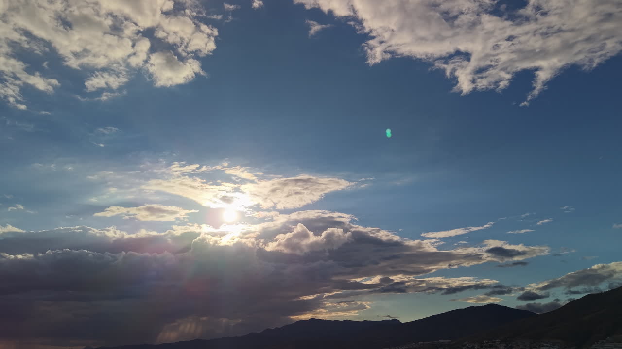 Cielo drammatico con raggi di sole che filtrano tra le nuvole su un paesaggio montano vicino a Benidorm, creando una scena naturale suggestiva